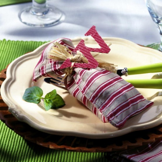 a creative place setting with a patterned brown and white plate, a green placemat and a striped napkin is a cool and bold idea for Thanksgiving