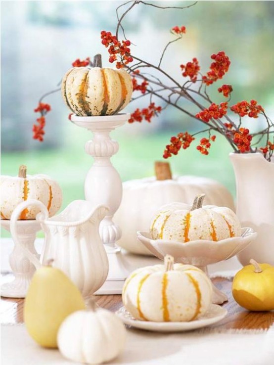 traditional Thanksgiving decor with elegant white tableware, red berries on branches and mini pumpkins on stands is a lovely idea that always works