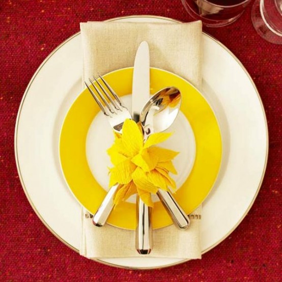 a large white and a mustard and white plate paired with a neutral napkin for a modern Thanksgiving place setting with a touch of color