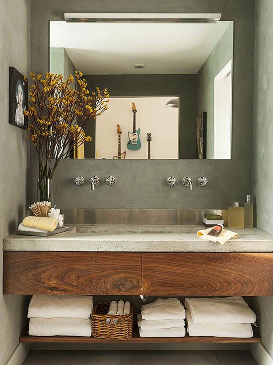 a rustic bathroom with concrete walls and a concrete countertop on the wooden vanity, with a large mirror and a shelf for storage