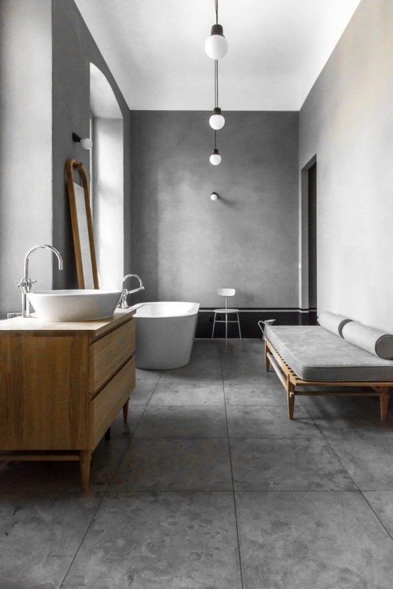 a minimalist bathroom with concrete walls, concrete tiles on the floor, a sleek vanity and a daybed, a chic bathtub