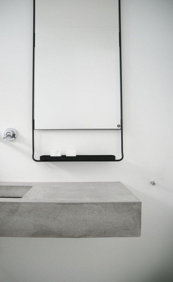 a floating concrete vanity with a sink, a black metal shelf with soaps for an ultra-minimalist bathroom