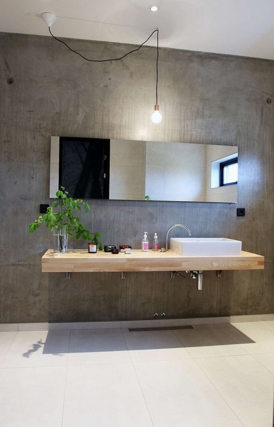 a contemporary bathroom with a concrete wall, a floating wooden vanity, a mirror, some lights and a square sink