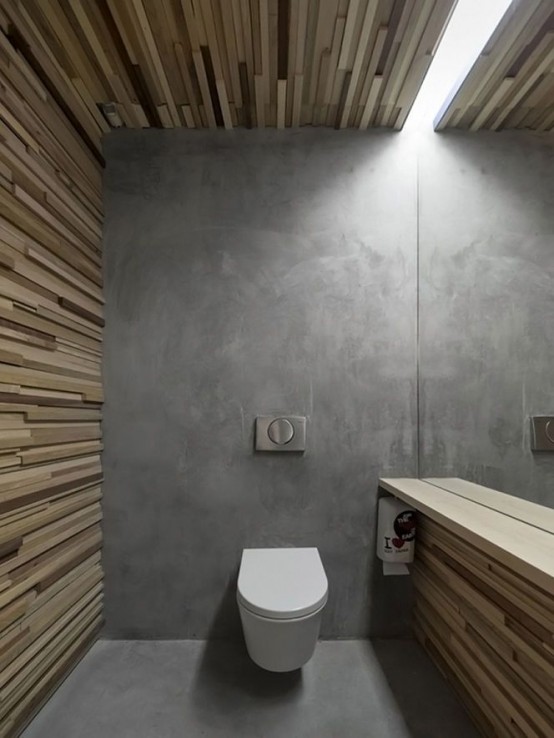 a minimalist bathroom done with a concrete wall and floor and with textural wooden planks on the walls and a ceiling plus a skylight is cool and bold