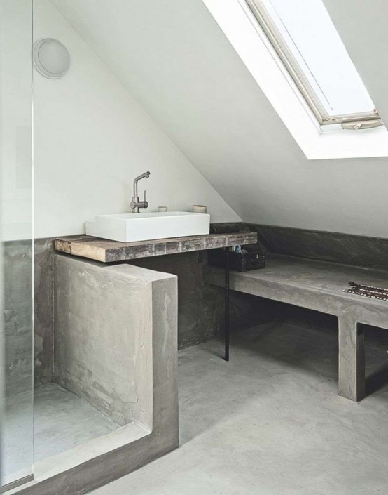 a minimalist attic bathroom with a concrete floor and half wall in the shower space, a concrete bench and a wooden vanity with a square sink