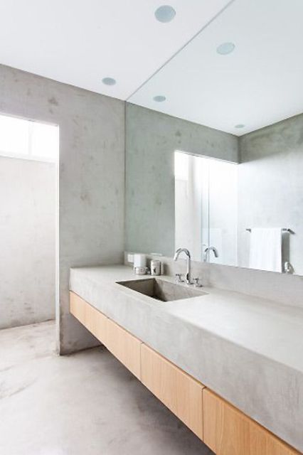 a minimalist concrete bathroom with a large floating vanity with a cocnrete countertop and a built-in sink is cool and chic