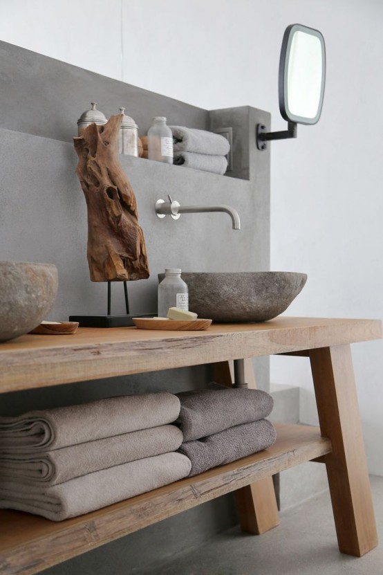 a contemporary bathroom with a concrete wall, a wooden vanity with storage and stone carved sinks is a stylish space