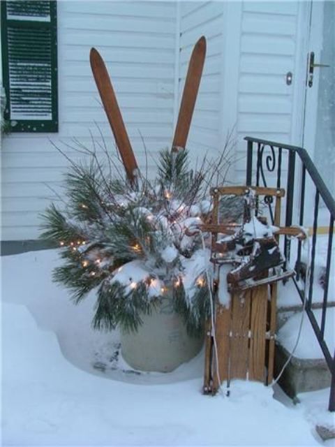 a bucket with evergreens, lights, twigs, a sleigh and skates for lovely rustic and a bit vintage decor outdoors