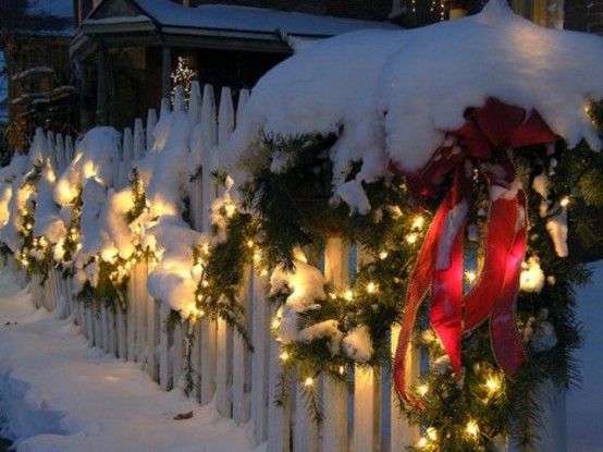 an evergreen and light garland with red bows is a lovely outdoor Christmas decoration you can easily make
