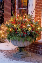 an oversized vintage urn with greenery, evergreens, red twigs and berries is a lovely decoration for outdoors to make  a statement at Christmas
