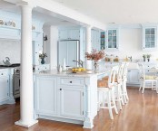 an airy light blue cottage kitchen with vintage cabinets, white vintage stools and pillars for a refined touch in the space
