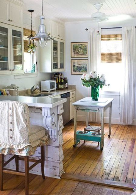 a vintage cottage kitchen in neutrals, with a small cart kitchen island, shabby chic raised countertop for having meals and vintage stools