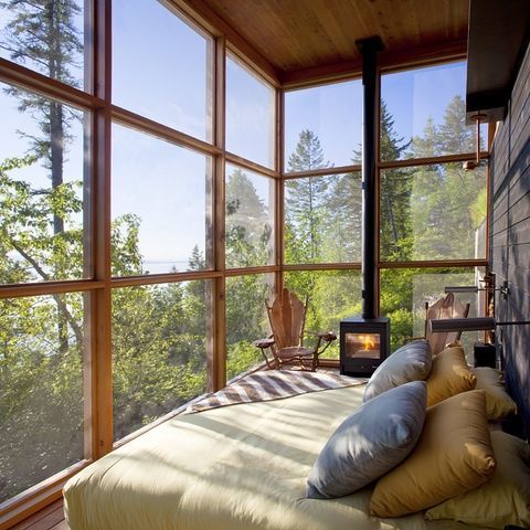a dreamy sunroom bedroom with glazed walls, a bed with pillows and a hearth for comfortable sleeping is awesome