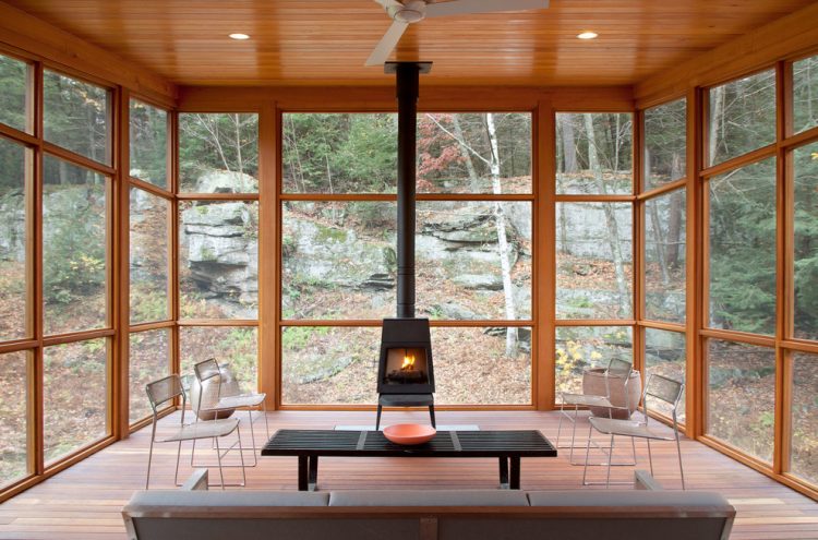 super cozy sunroom filled with natural wood and a wood-burning stove