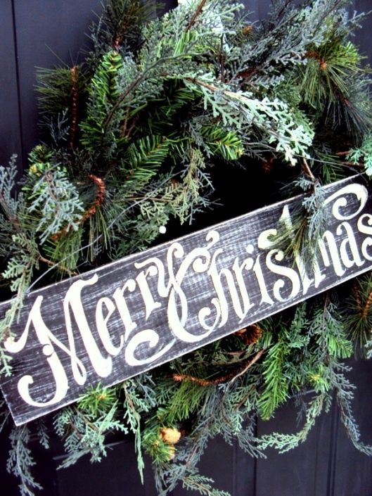 an evergreen Christmas wreath accented with a chalkboard sign is a stylish rustic holiday decor idea