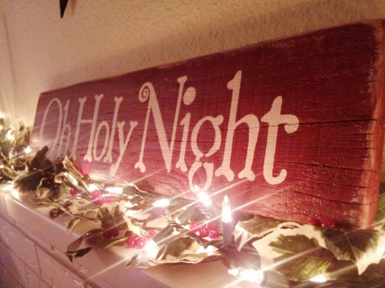 a red Christmas sign with white letters is a lovely decor idea for this mantel, paired up with an evergreen garland with lights and pinecones