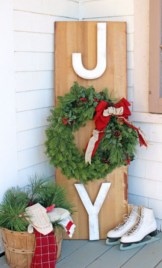 a lovely outdoor Christmas sign of wood, with large letters and an evergreen wreath with a red bow as an O letter