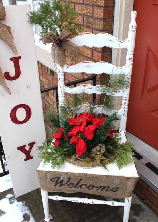 a white Christmas sign with red letters and a burlap bow on top is a stylish rustic decor idea for a holiday outdoor space like a porch