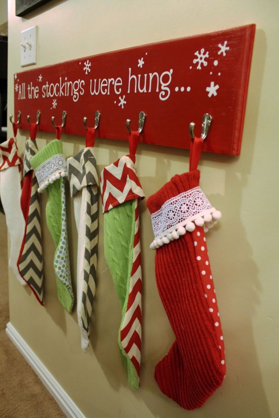 a red Christmas sign with hooks and stockings with a quote is a lovely decor idea for a holiday home, especially if you have kids