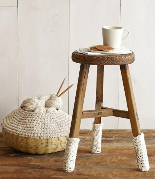 a dark-stained stool with white crochet cozies and a basket with a crocheted top are a great combo for styling a space for fall and winter