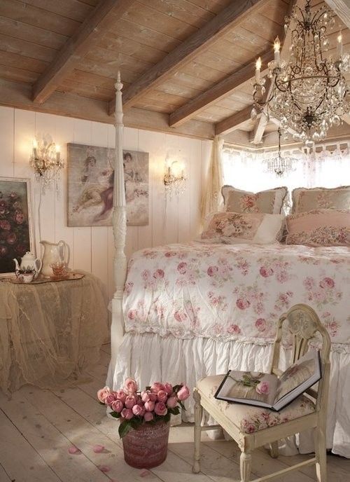 a neutral shabby chic bedroom with exquisite white furniture, a crystal chandelier, floral artworks and floral bedding