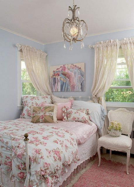 a pastel shabby chic bedroom with exquisite white furniture, neutral and floral textiles and a crystal chandelier