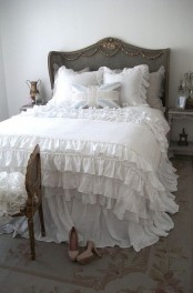 a simple and neutral shabby chic bedroom with refined shabby chic furniture, a printed rug and neutral ruffle bedding