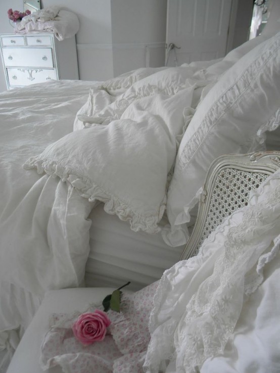 a white shabby chic bedroom with refined furniture, white lace and ruffle bedding and floral touches