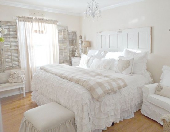 a white shabby chic bedroom with shabby shutters on the walls, sophisticated neutral furniture, white ruffle bedding and chic details
