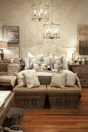 a vintage rustic bedroom with wooden furniture, pendant lamps, lots of artworks and printed chests at the foot of the bed