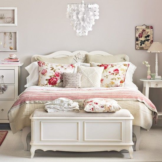 a romantic neutral bedroom with grey walls, white furniture in vintage style, a shell chandelier and floral bedding for a romantic feel