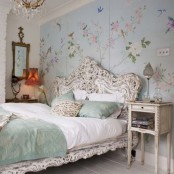 a refined vintage bedroom with a floral statement wall, refined shabby chic and vintage furniture, a crystal chandelier, a mirror and a lamp