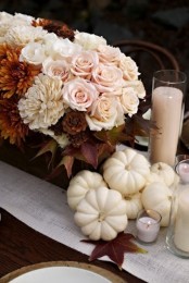 white gourds, white linens, roses and candles paired with darker blooms and leaves make up a chic and stylish Thanksgiving tablescape
