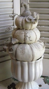 a porcelain bowl with white pumpkins stacked, twigs and glitter makes up a chic and beautiful Thanksgiving decoration in vintage style