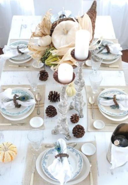white linens, pumpkins, corn husks and white candles, pinecones and woven placemats for a chic and beautiful look