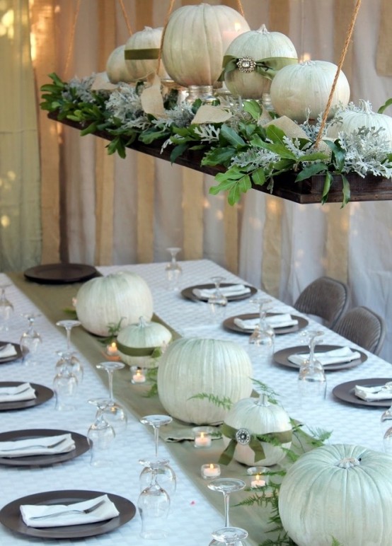 white linens, white pumpkins and candles and a pretty overhead pumpkin installation with greenery for a beautiful Thanksgiving tablescape