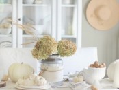a natural white Thanksgiving tablescape with white pumpkins, gourds, linens and some bowls and plates for decor