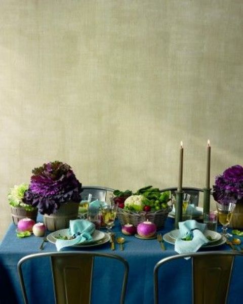 a refined farmhouse Thanksgiving tablescape with a teal tablecloth, greenery, purple blooms and veggies, grey candles and mint napkins