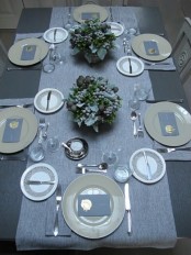 a stylish slate grey and blue Thanksgiving tablescape with a silver table runner, grey napkins and floral arrangements