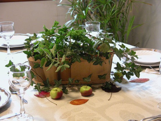 a very simple last minute Thanksgiving or fall centerpiece of a box with greenery and some fall leaves and apples around is very cool