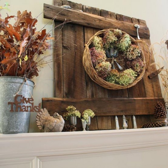 a rustic Thanksgiving mantel with dried hydrangeas, turkeys, dried leaves, twigs, pinecones and some spoons and a basket with blooms
