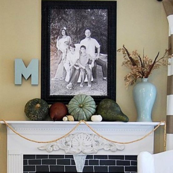 a natural and rustic Thanksgiving mantel with natural pumpkins and gourds, wooden bead garlands, a letter and some feathers and dried leaves