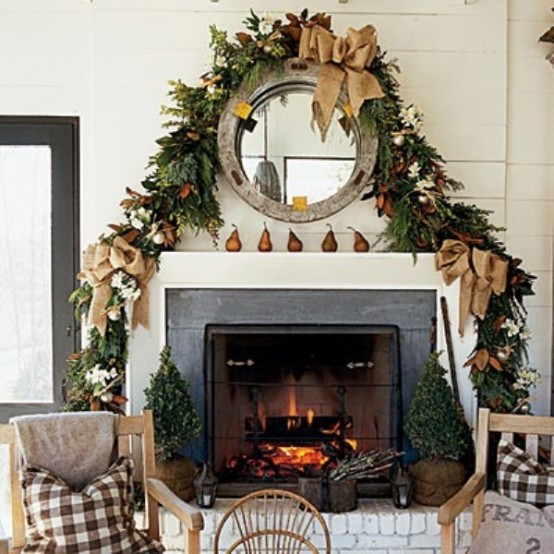 a fall to Christmas mantel with pears and a lush greenery and magnolia leaf garland plus a large burlap bow is a lovely idea
