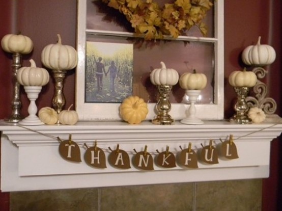 a fall or Thanksgiving mantel with white and metallic stands, faux pumpkins, a leaf garland with letters is a lovely decoration