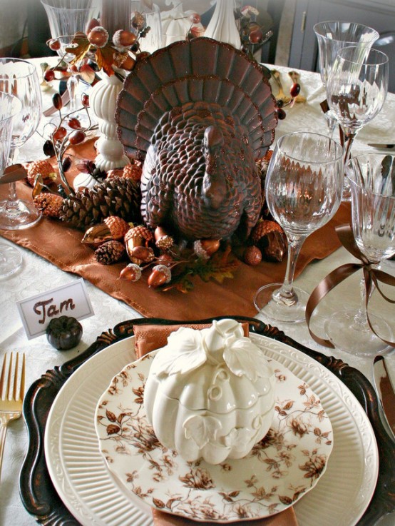 a vintage Thanksgiving tablescape with vintage chargers, a rust-colored napkin and neutral linens, porcelain decor, faux acorns and nuts