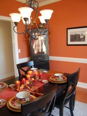 a bold Thanksgiving tablescape with bright linens, printed porcelain, faux pumpkins, leaves and bold pillar candles is a chic and stylish idea