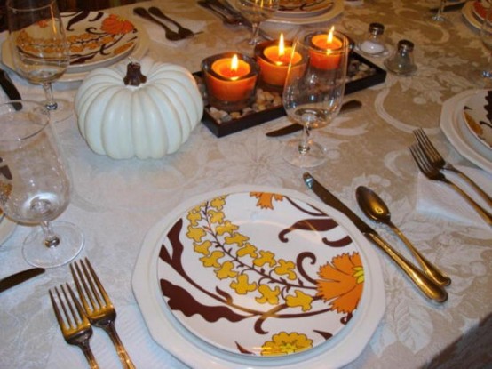 a neutral vintage Thanksgiving tablescape with printed plates, neutral linens, faux pumpkins and a cool and cozy candle centerpiece
