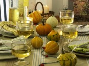 a neutral and natural Thanksgiving tablescape with natural gourds and pumpkins, a green tablecloth and napkins, neutral porcelain and pillar candles