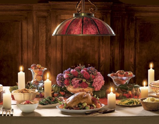 a sophisticated traditional Thanksgiving tablescape with a bold floral centerpiece, candles, pillar candles and a beautiful metal pendant lamp over it