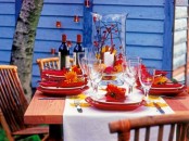 a colorful Thanksgiving tablescape with red porcelain, napkins, blooms, fall leaves and berries is a bright solution
